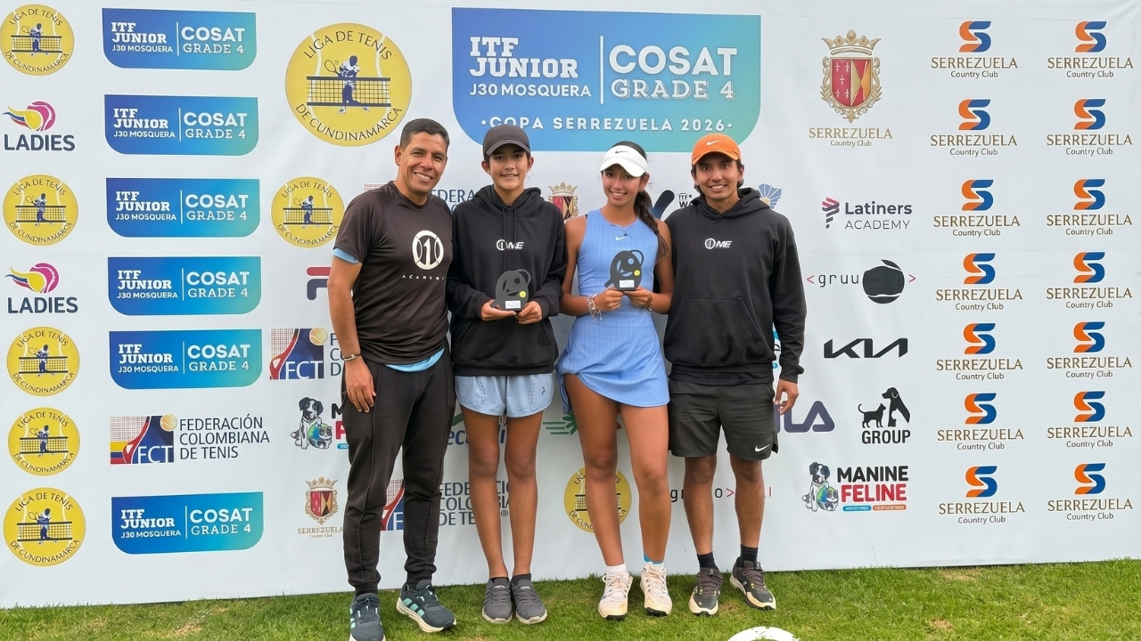 Cuatro tenistas posan sonrientes frente a un muro publicitario del torneo ITF Junior / COSAT en Mosquera. Las dos jóvenes en el centro sostienen trofeos, flanqueadas por dos hombres con ropa deportiva.